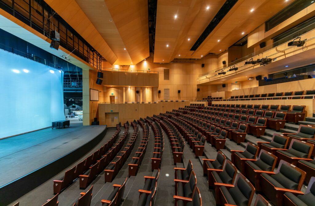 event space with a lot of rolls of chairs and a big stage in front