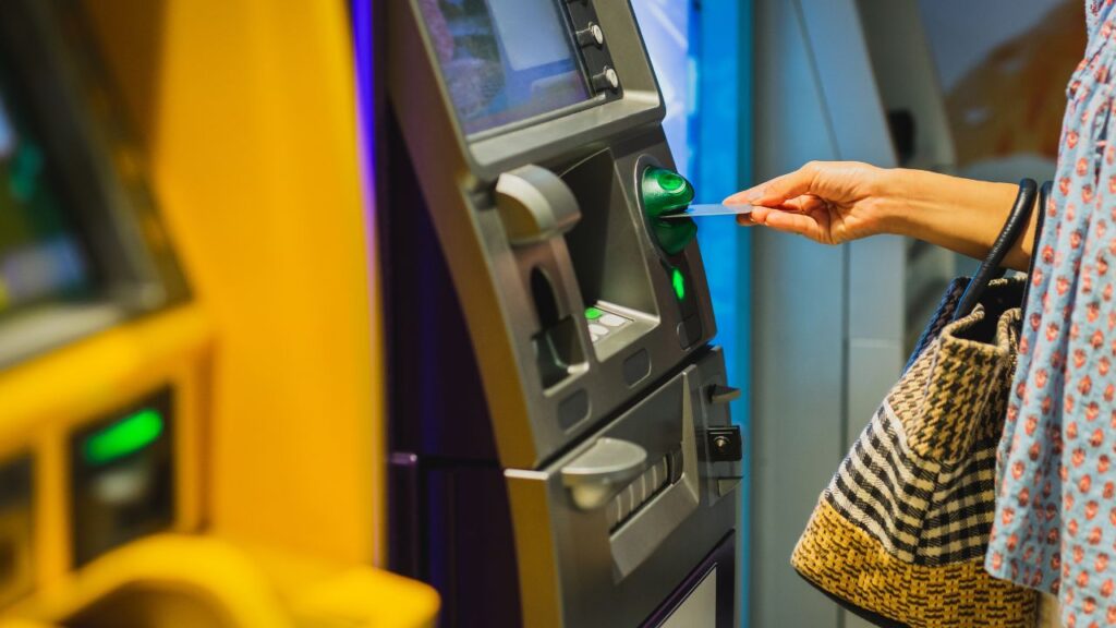 close up of a woman inserting her card into an atm 