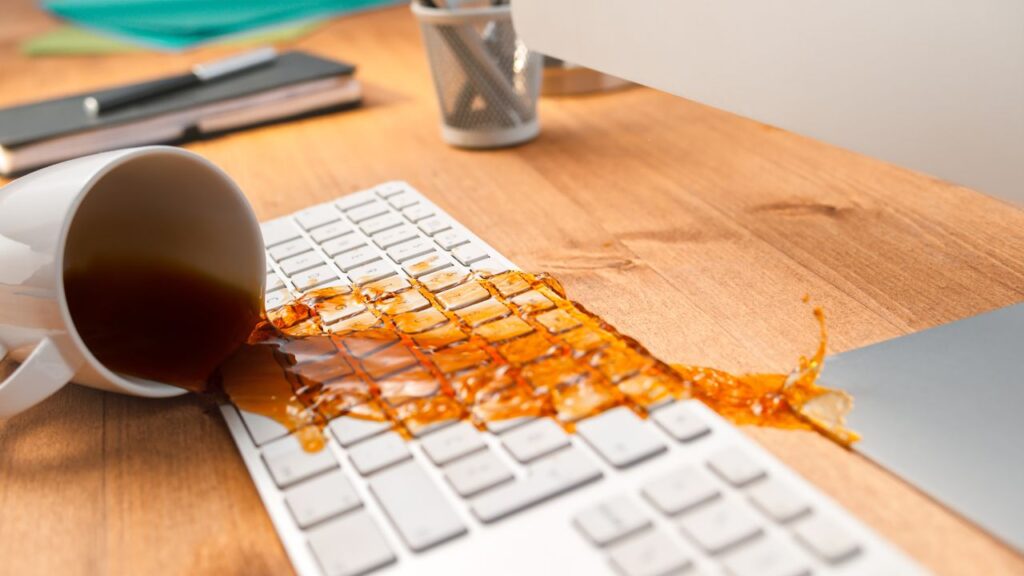 coffee cup falling into computer keyboard and spilling the content onto the keyboard