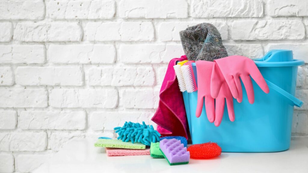 bucket full of cleaning supplies such as safety gloves, sponges and cloths