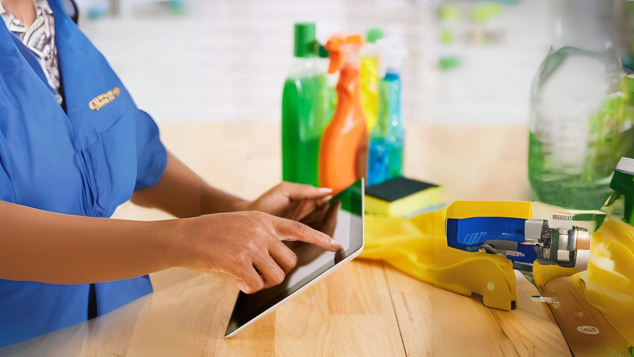 woman wearing a janitorial staff uniform looking in an ipad cleaning app