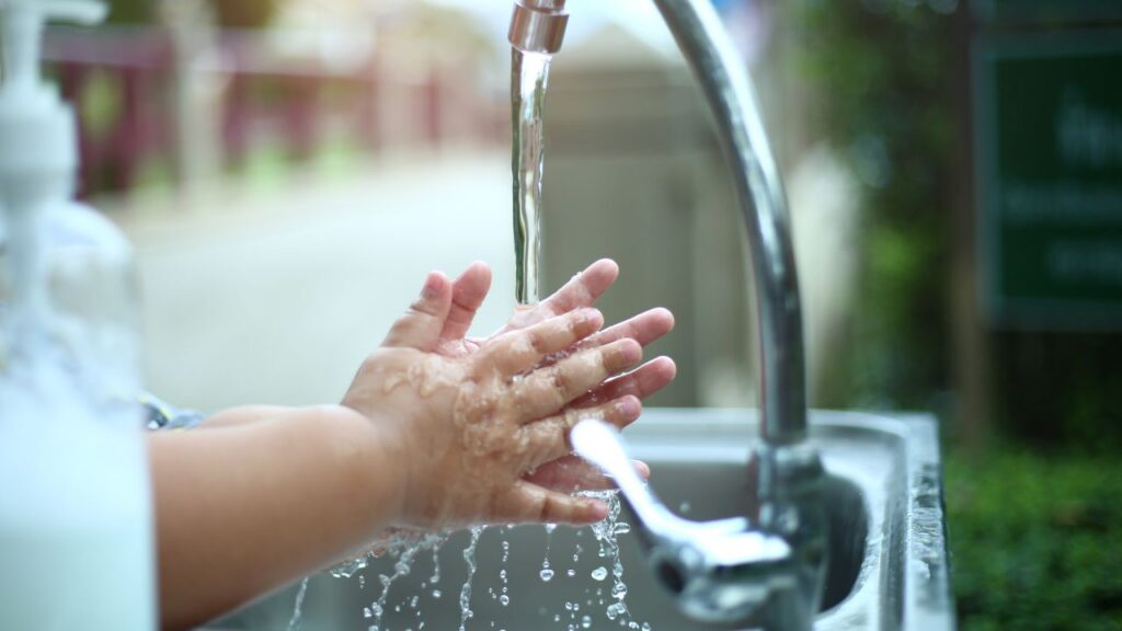 child washing their hands on a outdoor sink in their school