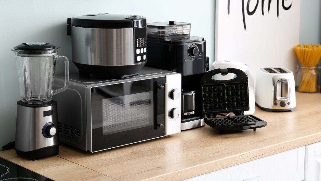 image of kitchen appliances that can be seen in an office environment like a microwave, blender, coffee maker and toster