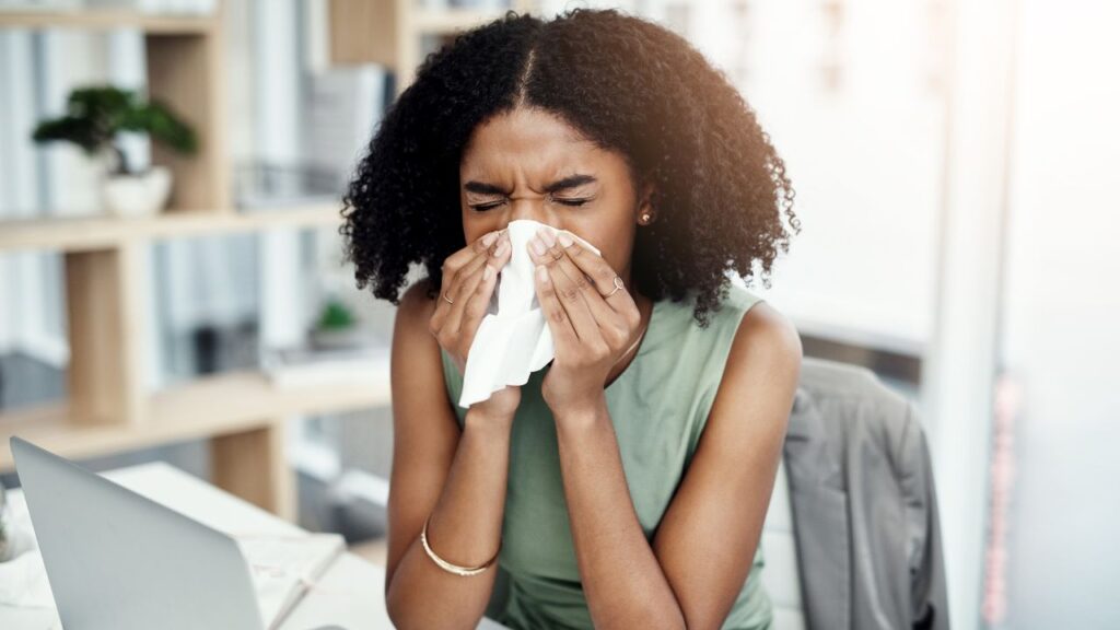 girl being sick at the office blowing her nose