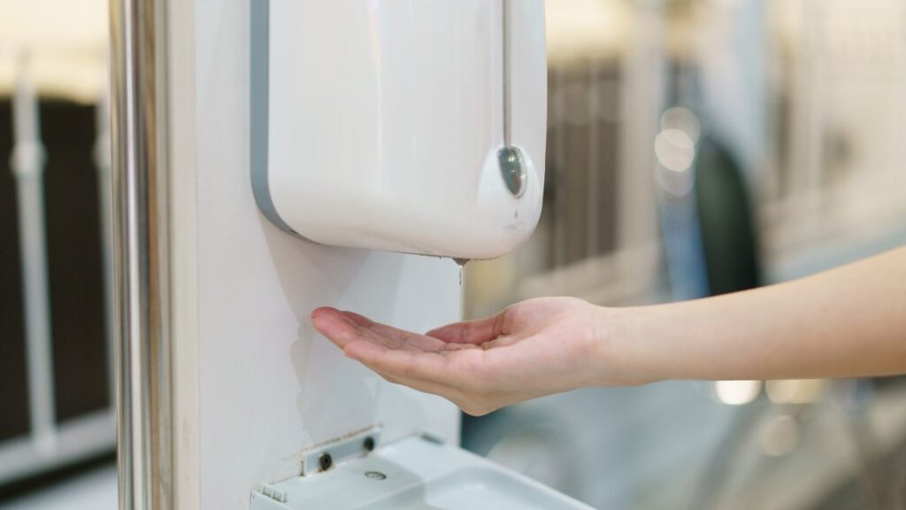 kid getting hand sanitizer in a automatic sanitizer as a way of ensuring cleaning large educational facilities