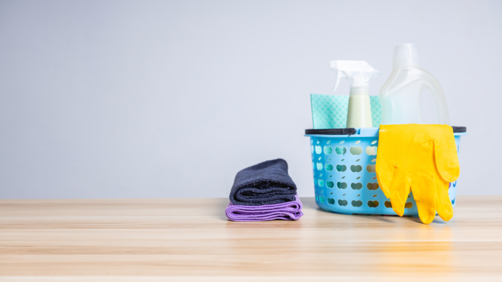 small basket with cleaning supplies such as microfiber cloths, gloves and a cleaning liquid