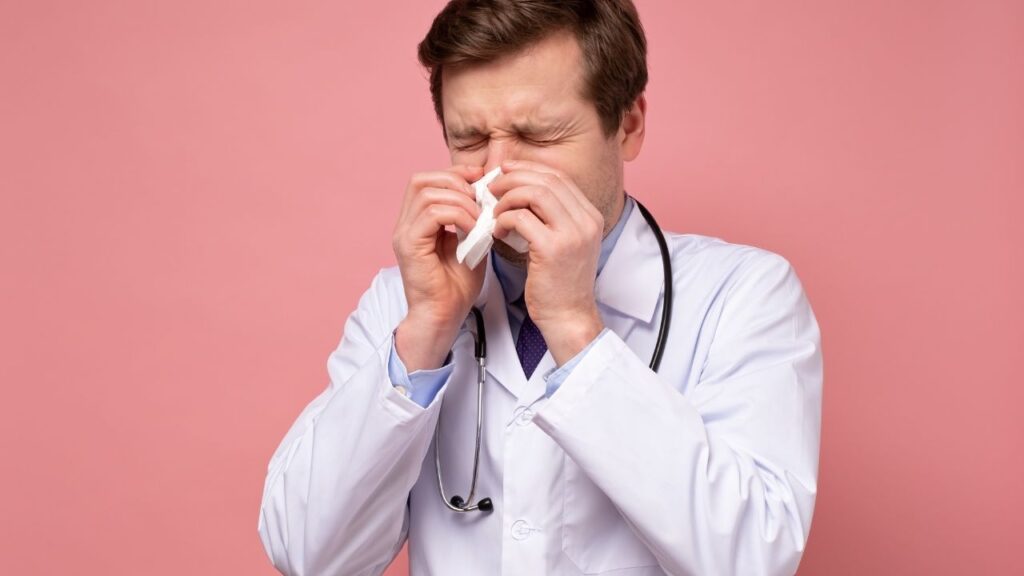 male doctor sneezing into a tissue