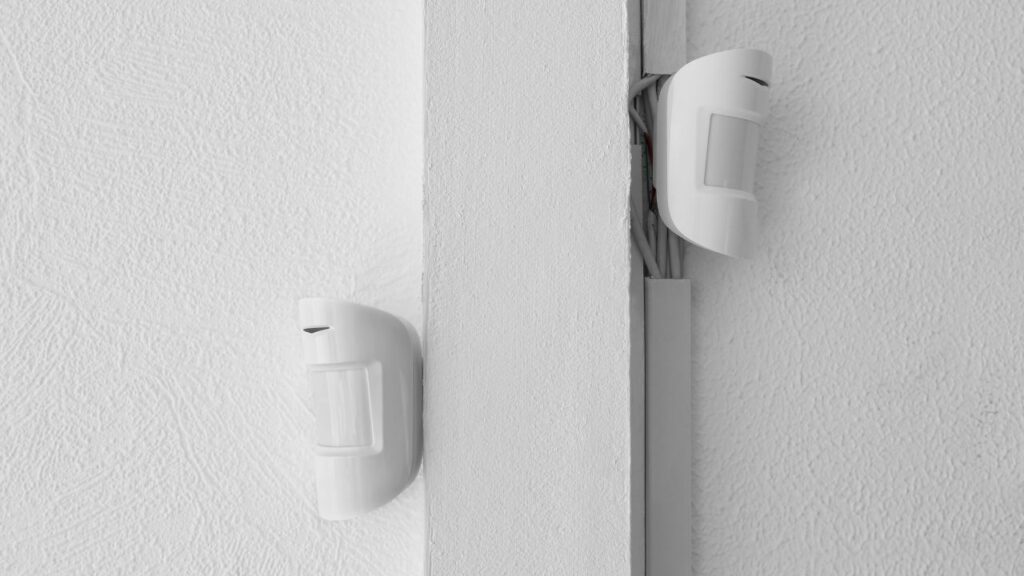 two smart sensors hung on a duct connected to the wall, all white, the sensors, wall and duct