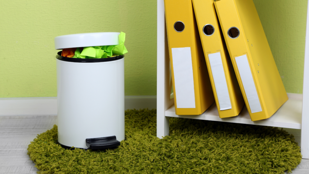 trash can close to a shlef with folders on an office space