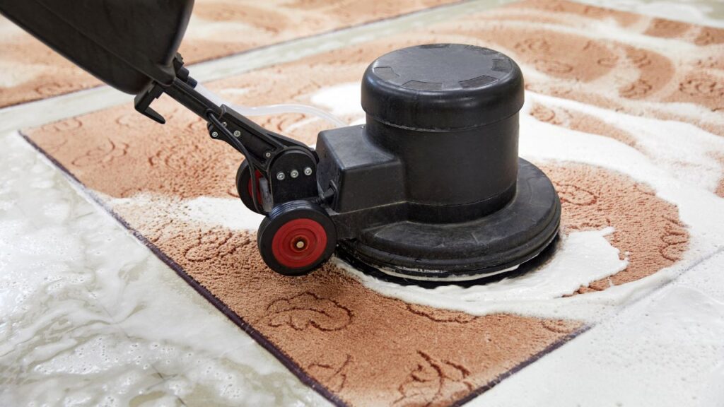 image of a light brown carpet with leaves pattern being washed with a machine showing an example of carpet cleaning used by commercial services