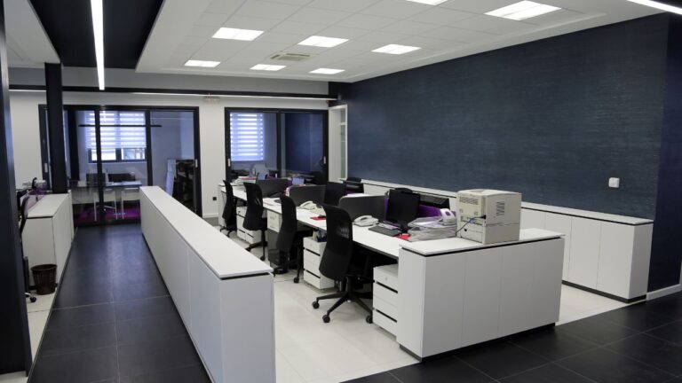 an office space with a central table with small cubicles with desktops and chairs ensuring an year-round office cleaning