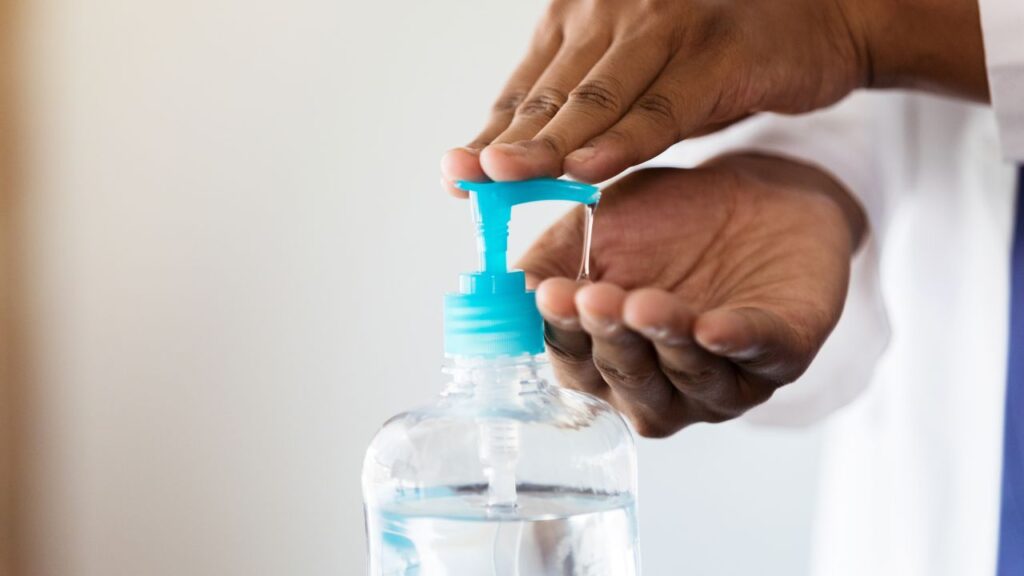 dark skinned doctor appling hand sanitizer onto his hands in a hospital environment