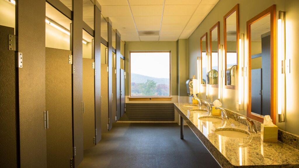 office restroom with stall doors on one side and multiple sinks and mirrors on the other