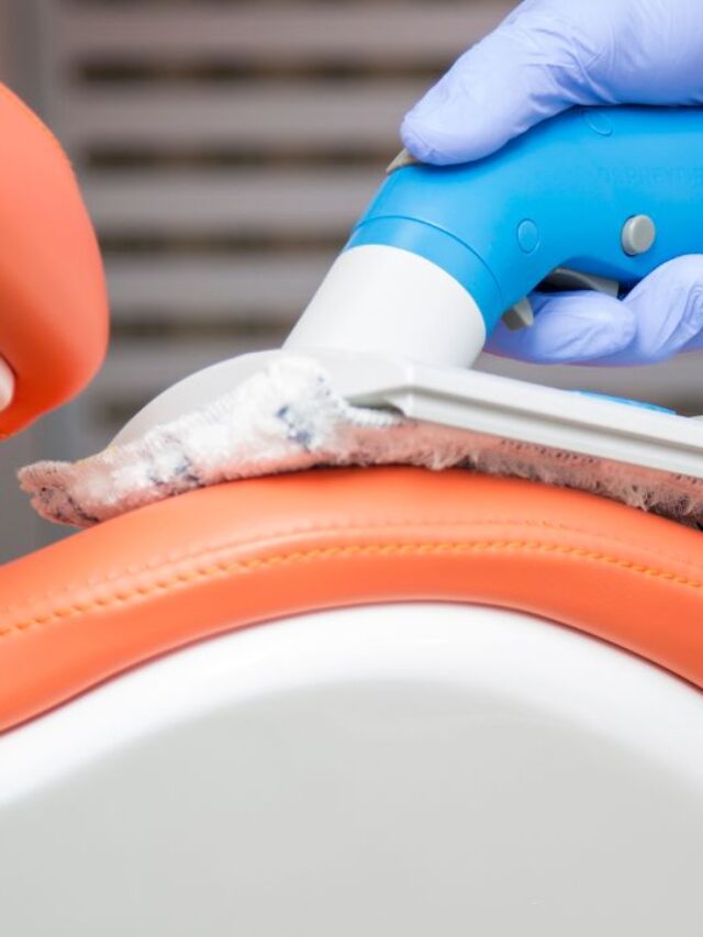 man cleaning a dental office chair with a portable vaccum cleaner