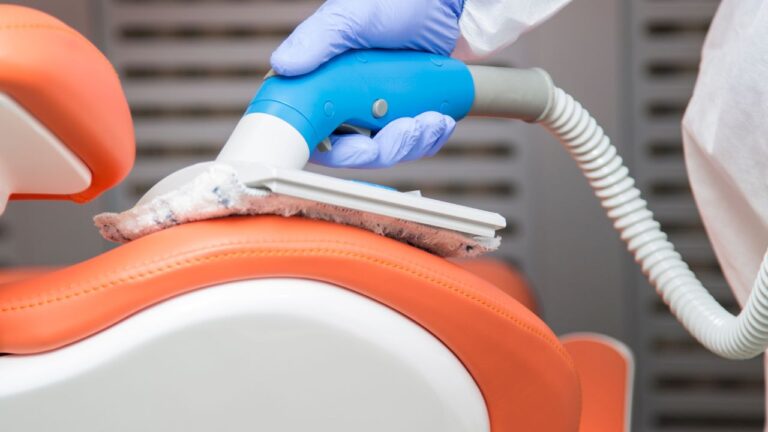 man cleaning a dental office chair with a portable vaccum cleaner