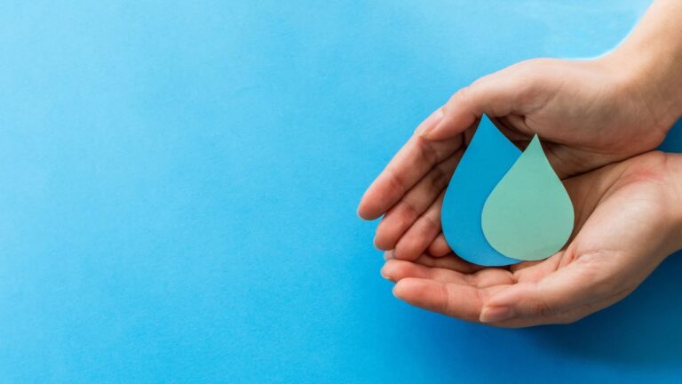 office water conservation showed with paper droplets of water being held by two hands