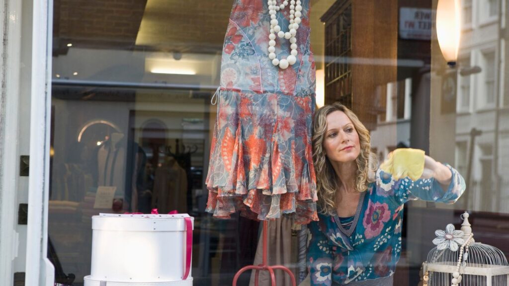 woman wiping storefront window clothing store