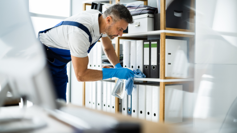 male cleaning staff cleaning shelf with documents