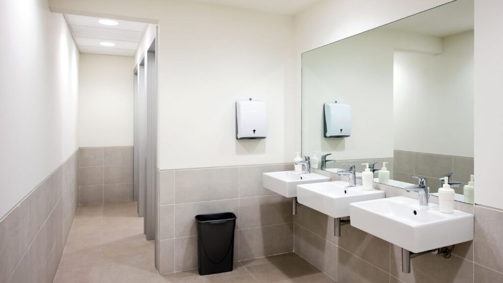 bathroom with three sinks and stalls